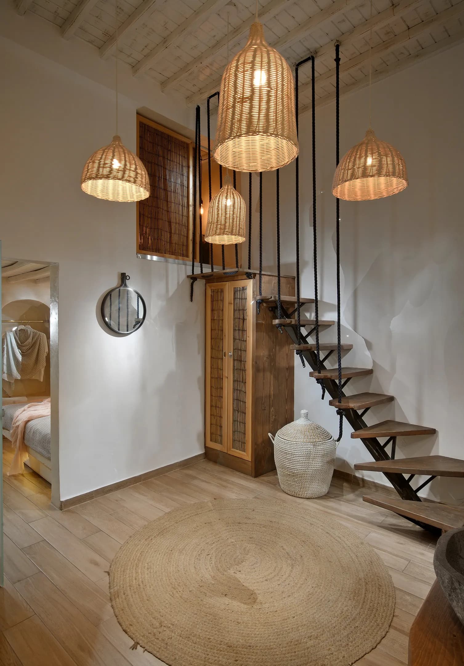 Maisonette living area with wooden stairs and rattan pendant lights
