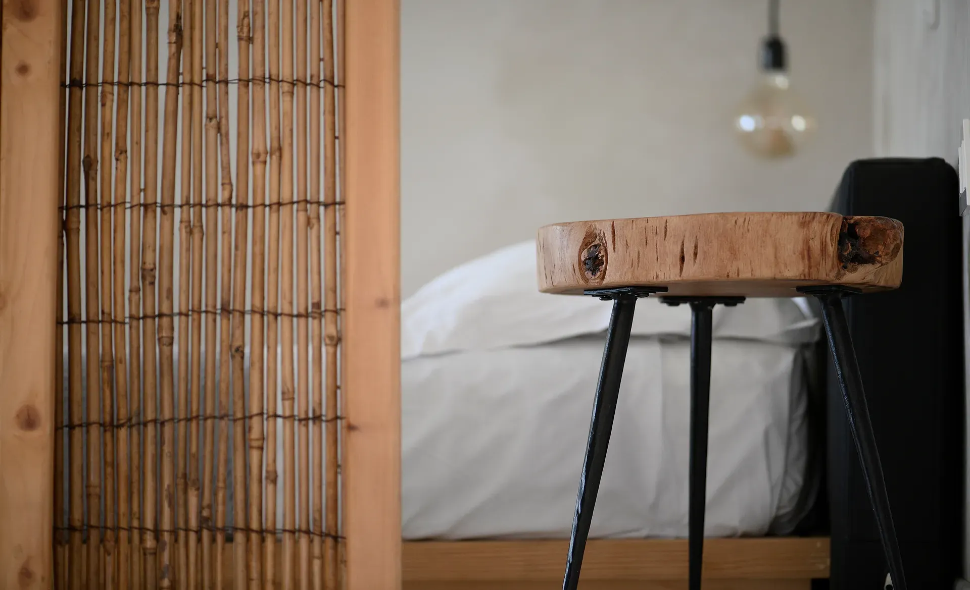 Wooden bedside stool next to a reed screen