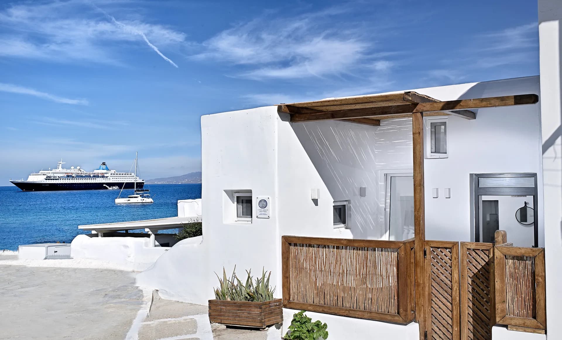 Whitewashed maisonette exterior with a reed-screened veranda by the sea
