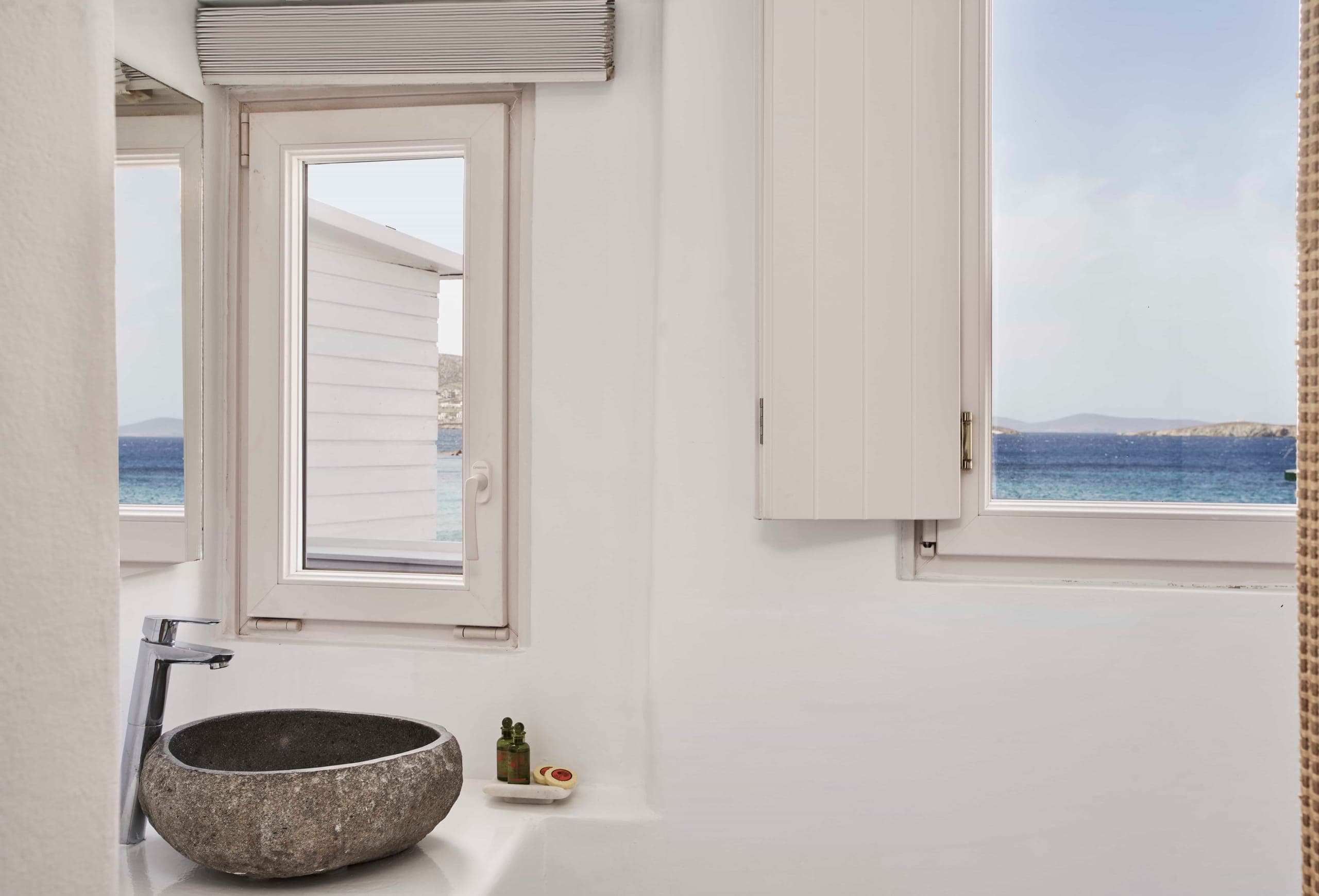 Stone basin beneath a window with a glimpse of the sea
