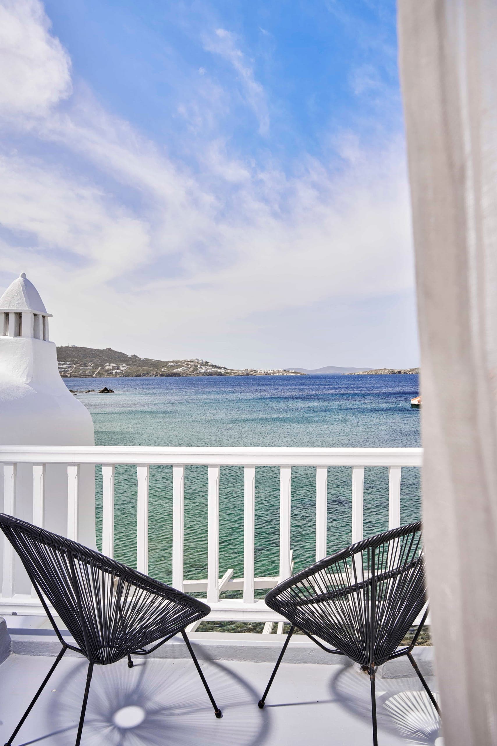 Two chairs on a white balcony above the sea