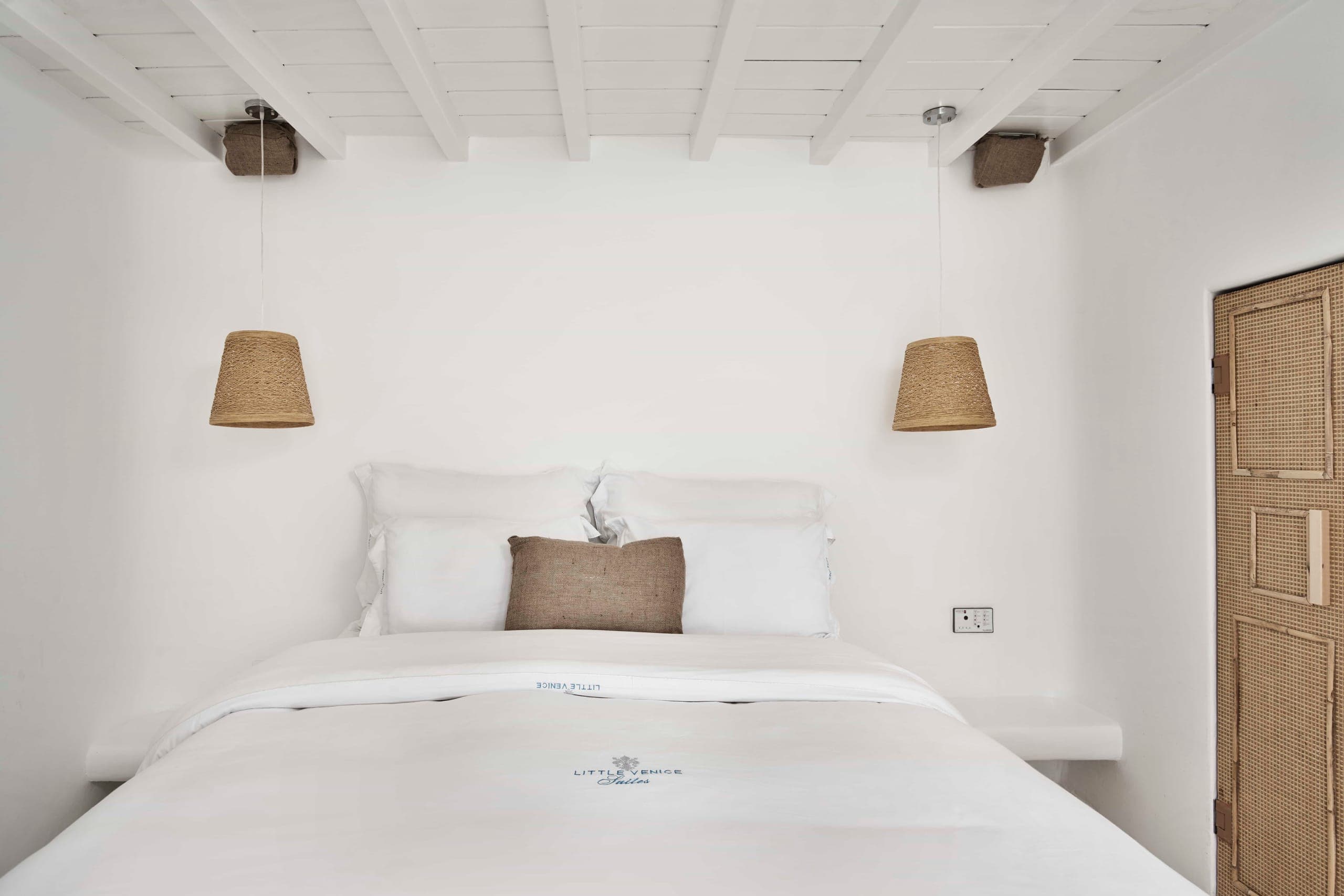 Queen bed with linen pillows and rattan pendant lamps