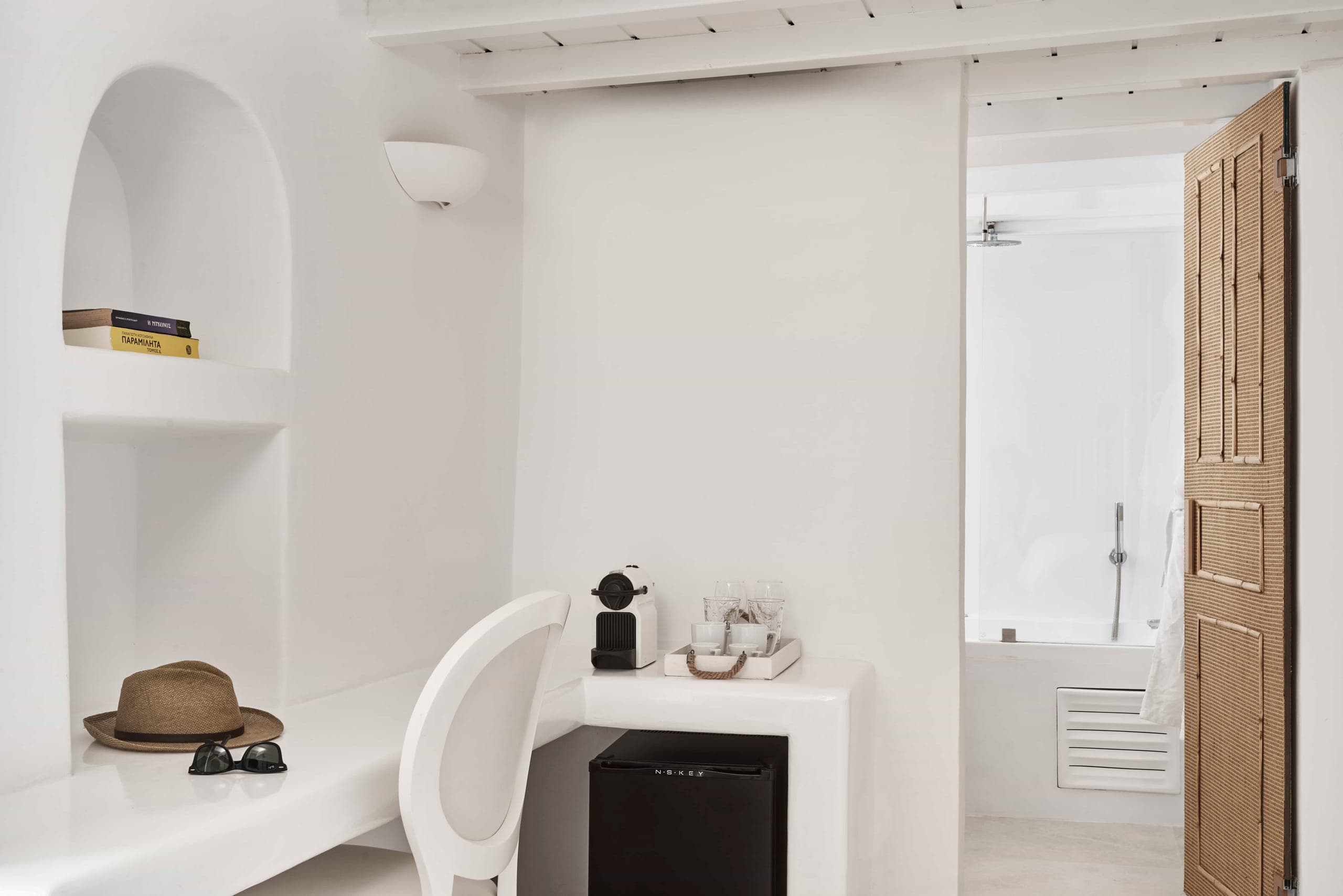 Desk, coffee machine and mini fridge beside the bathroom door