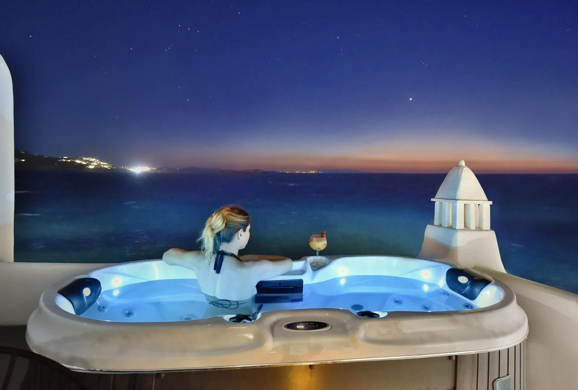 Guest in the outdoor Jacuzzi at night above the sea